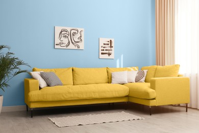 Image of Stylish living room with yellow comfortable sofa and light blue wall. Interior design