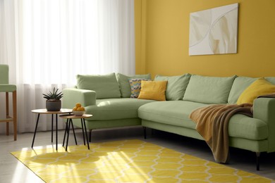 Image of Stylish living room with comfortable sofa and yellow wall. Interior design