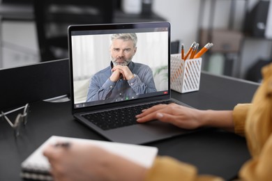 Image of Online psychologist. Woman receiving counselling via video call on laptop at table, closeup