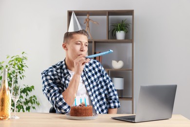 Photo of Happy man celebrating his birthday while having video call at desk indoors