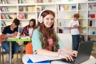 Photo of Student with laptop studying at table in library