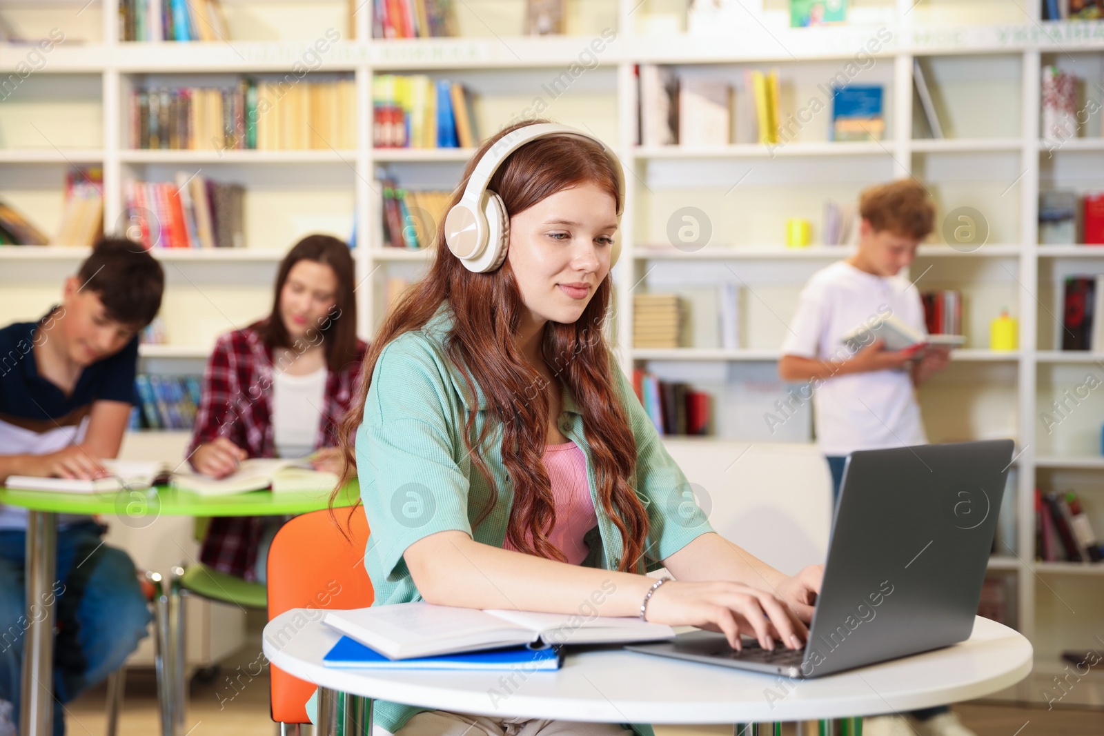 Student with laptop studying at table in library Photo of Student with laptop studying at table in library