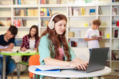 Photo of Student with laptop studying at table in library
