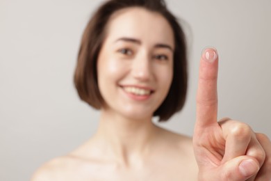 Photo of Woman with contact lens on light background, selective focus
