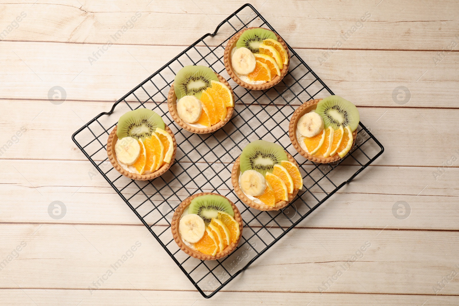 Tartlets with fruits on wooden table, top view. Delicious dessert Photo of Tartlets with fruits on wooden table, top view. Delicious dessert