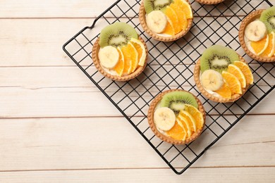 Photo of Delicious dessert. Tartlets with fruits on wooden table, top view. Space for text