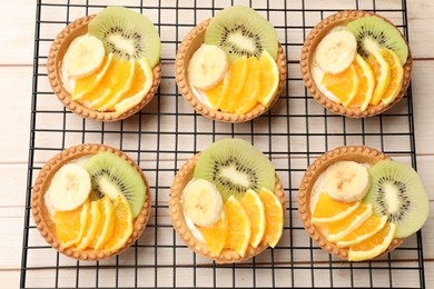 Photo of Tartlets with fruits on wooden table, top view. Delicious dessert