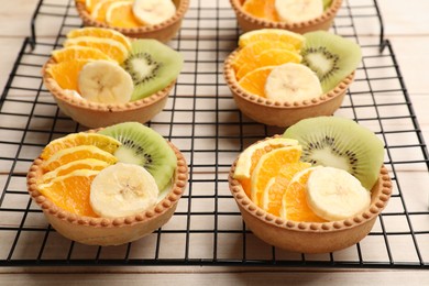 Photo of Tartlets with fruits on wooden table, closeup. Delicious dessert