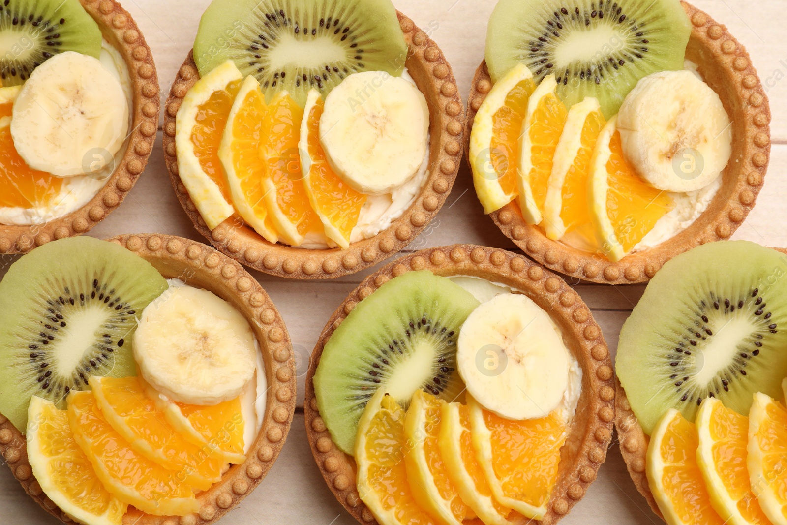 Tartlets with fruits on table, top view. Delicious dessert Photo of Tartlets with fruits on table, top view. Delicious dessert