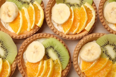Photo of Tartlets with fruits on table, top view. Delicious dessert