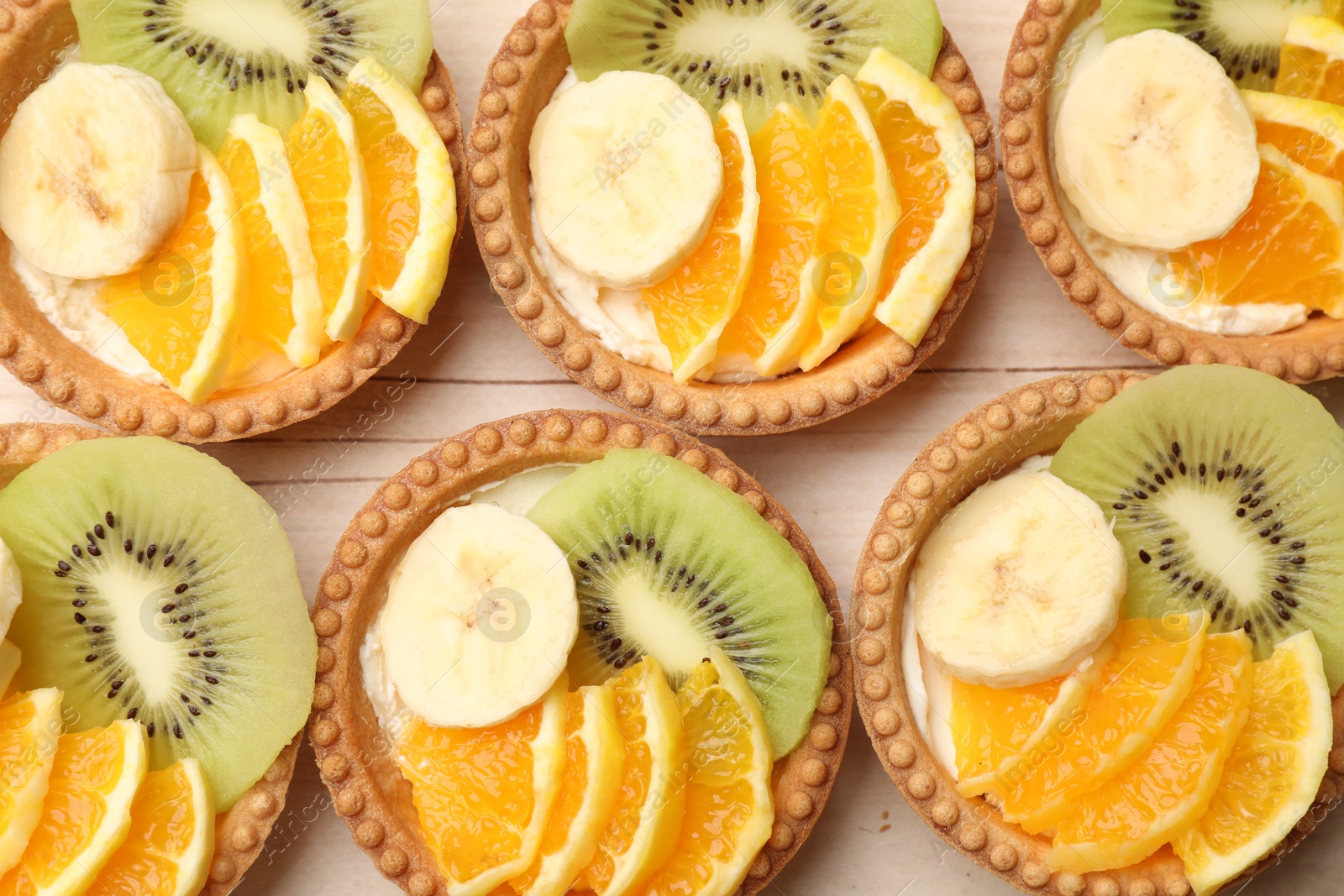 Tartlets with fruits on table, top view. Delicious dessert Photo of Tartlets with fruits on table, top view. Delicious dessert