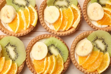 Photo of Tartlets with fruits on table, top view. Delicious dessert