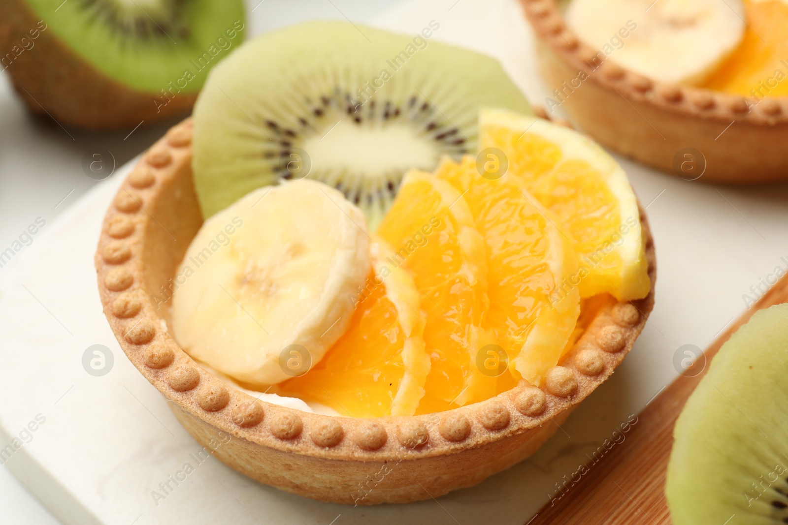 Tartlets with fruits on table, closeup. Delicious dessert Photo of Tartlets with fruits on table, closeup. Delicious dessert