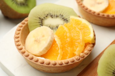 Photo of Tartlets with fruits on table, closeup. Delicious dessert