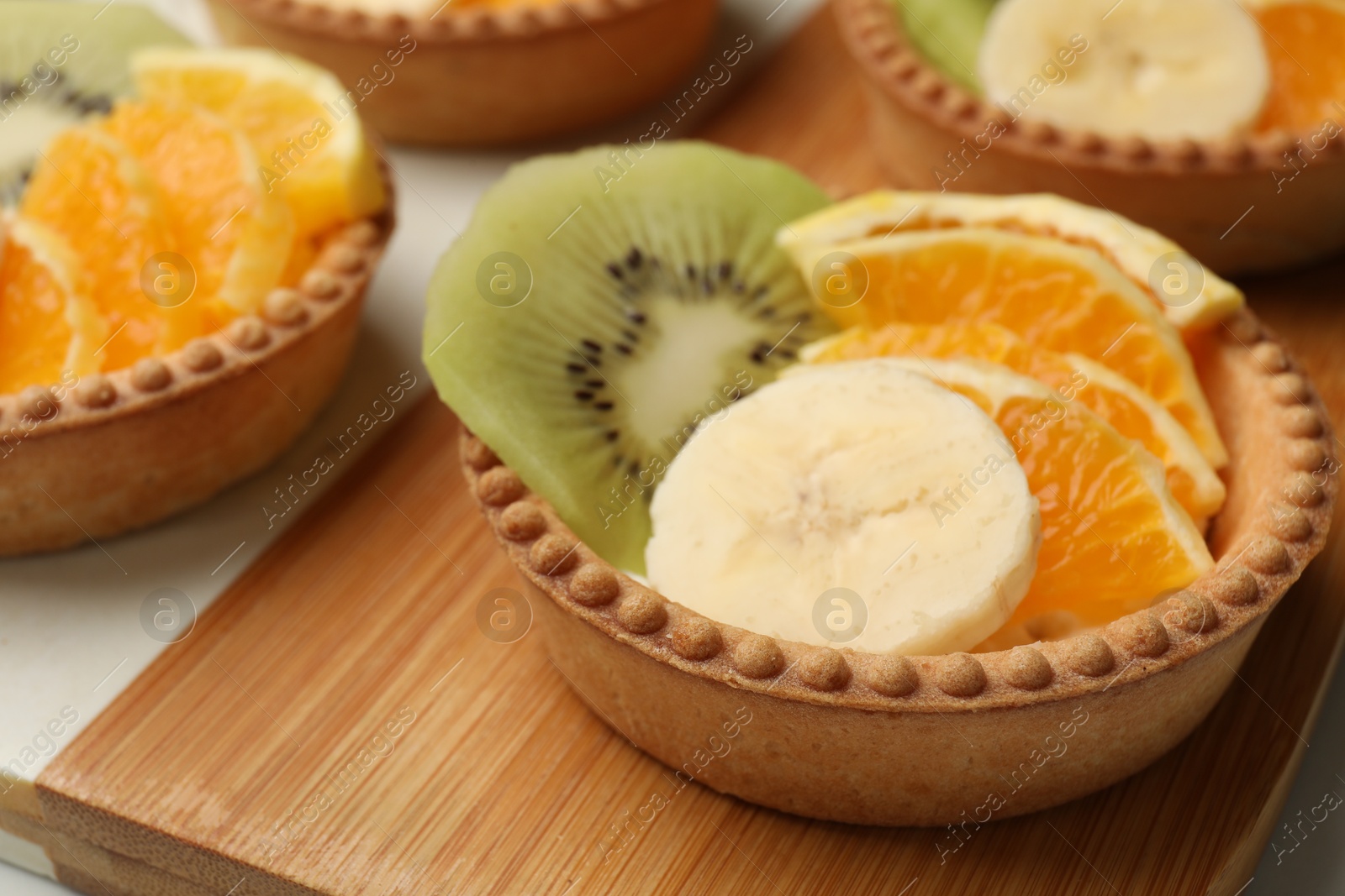 Tartlets with fruits on table, closeup. Delicious dessert Photo of Tartlets with fruits on table, closeup. Delicious dessert