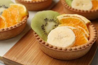 Photo of Tartlets with fruits on table, closeup. Delicious dessert