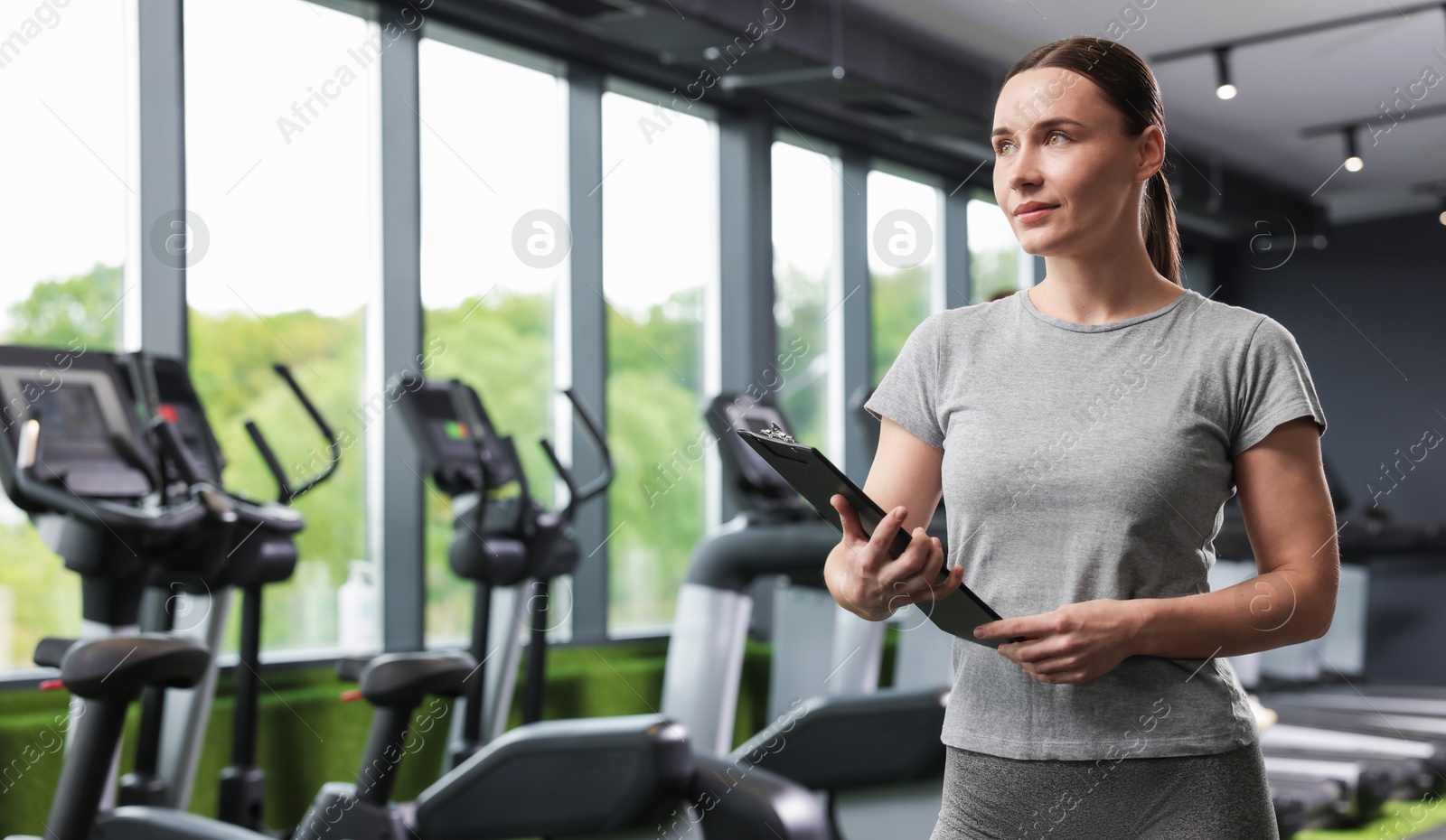 Professional personal trainer with clipboard in gym. Space for text Photo of Professional personal trainer with clipboard in gym. Space for text