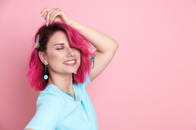 Photo of Beautiful woman with bright dyed hair on pink background, space for text