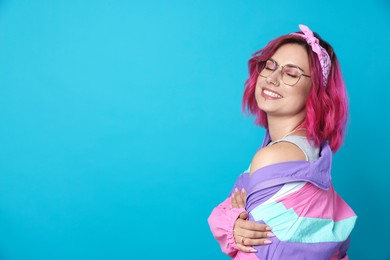 Photo of Beautiful woman with pink dyed hair in glasses on light blue background, space for text
