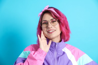 Photo of Beautiful woman with pink dyed hair in glasses on light blue background