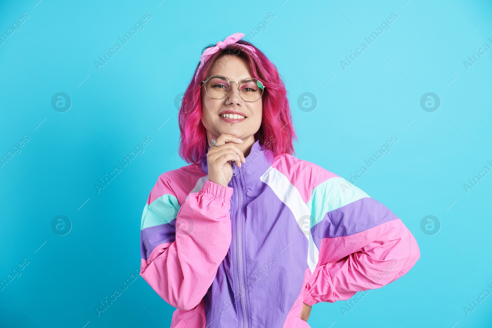 Beautiful woman with pink dyed hair in glasses on light blue background Photo of Beautiful woman with pink dyed hair in glasses on light blue background