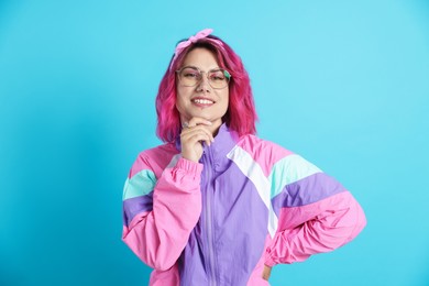 Photo of Beautiful woman with pink dyed hair in glasses on light blue background
