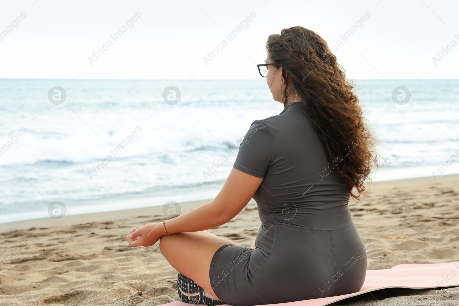 Woman meditating on sandy beach by sea Photo of Woman meditating on sandy beach by sea