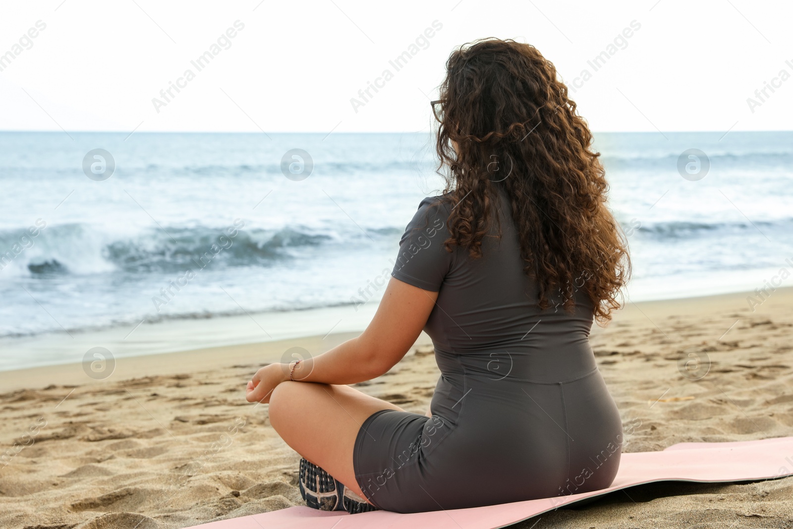 Woman meditating on sandy beach by sea Photo of Woman meditating on sandy beach by sea