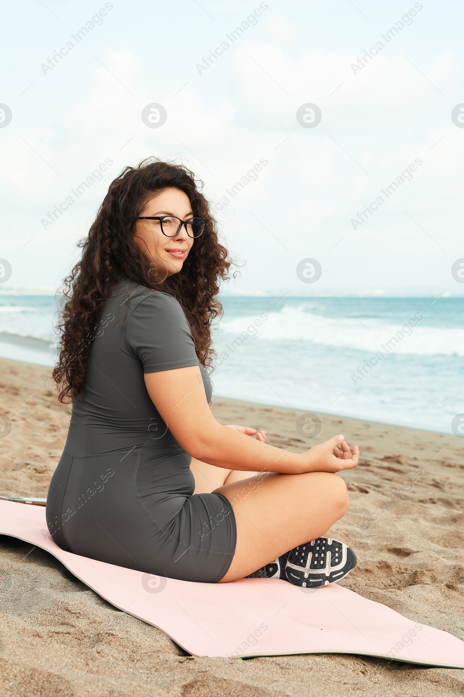 Woman meditating on sandy beach by sea Photo of Woman meditating on sandy beach by sea