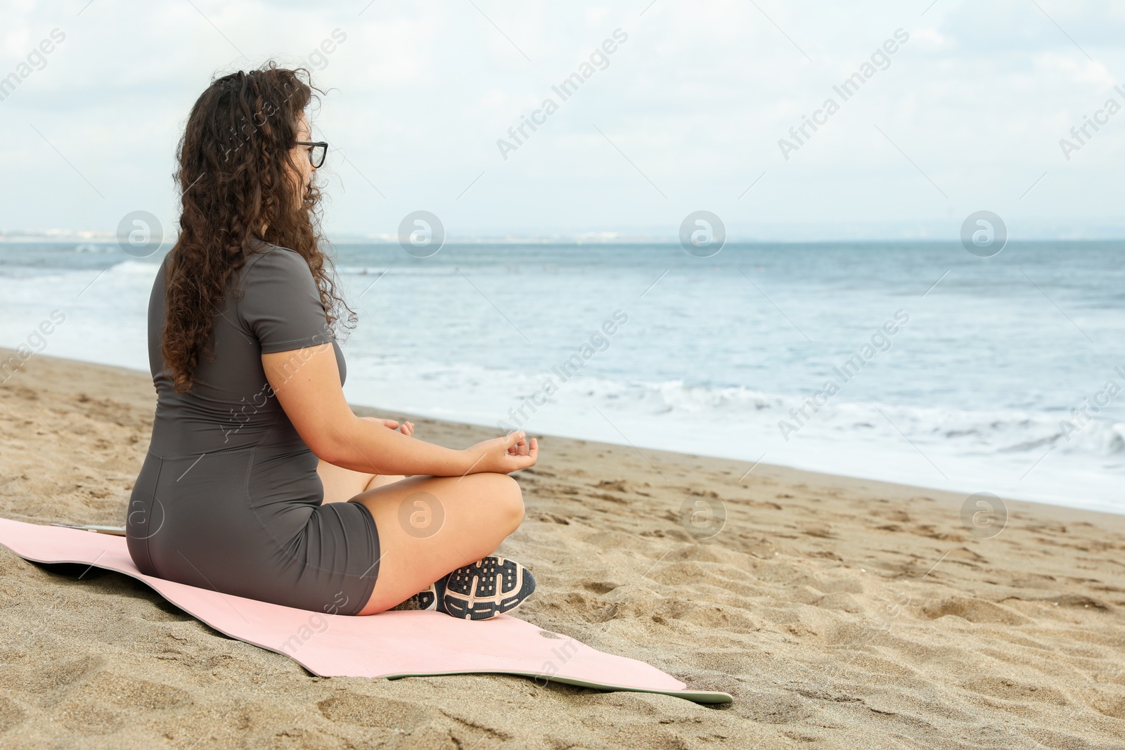Woman meditating on sandy beach by sea, space for text Photo of Woman meditating on sandy beach by sea, space for text