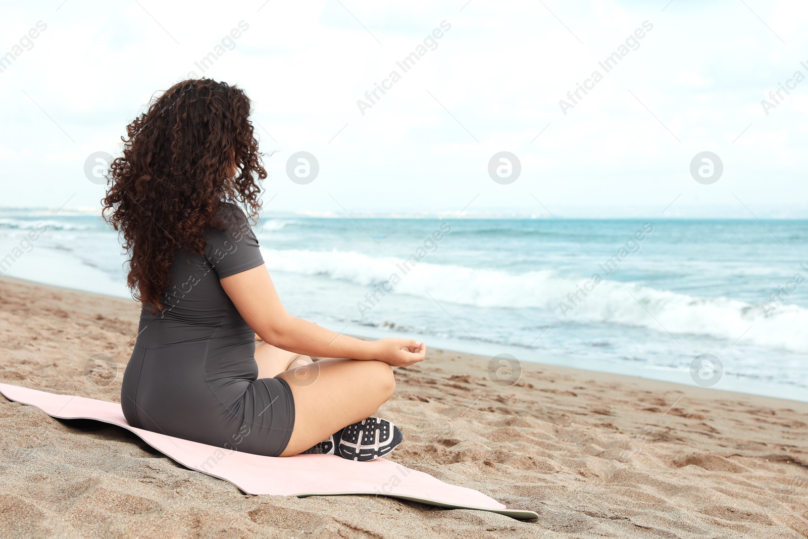 Woman meditating on sandy beach by sea, space for text Photo of Woman meditating on sandy beach by sea, space for text