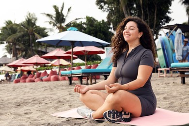 Photo of Beautiful young woman meditating on sandy beach