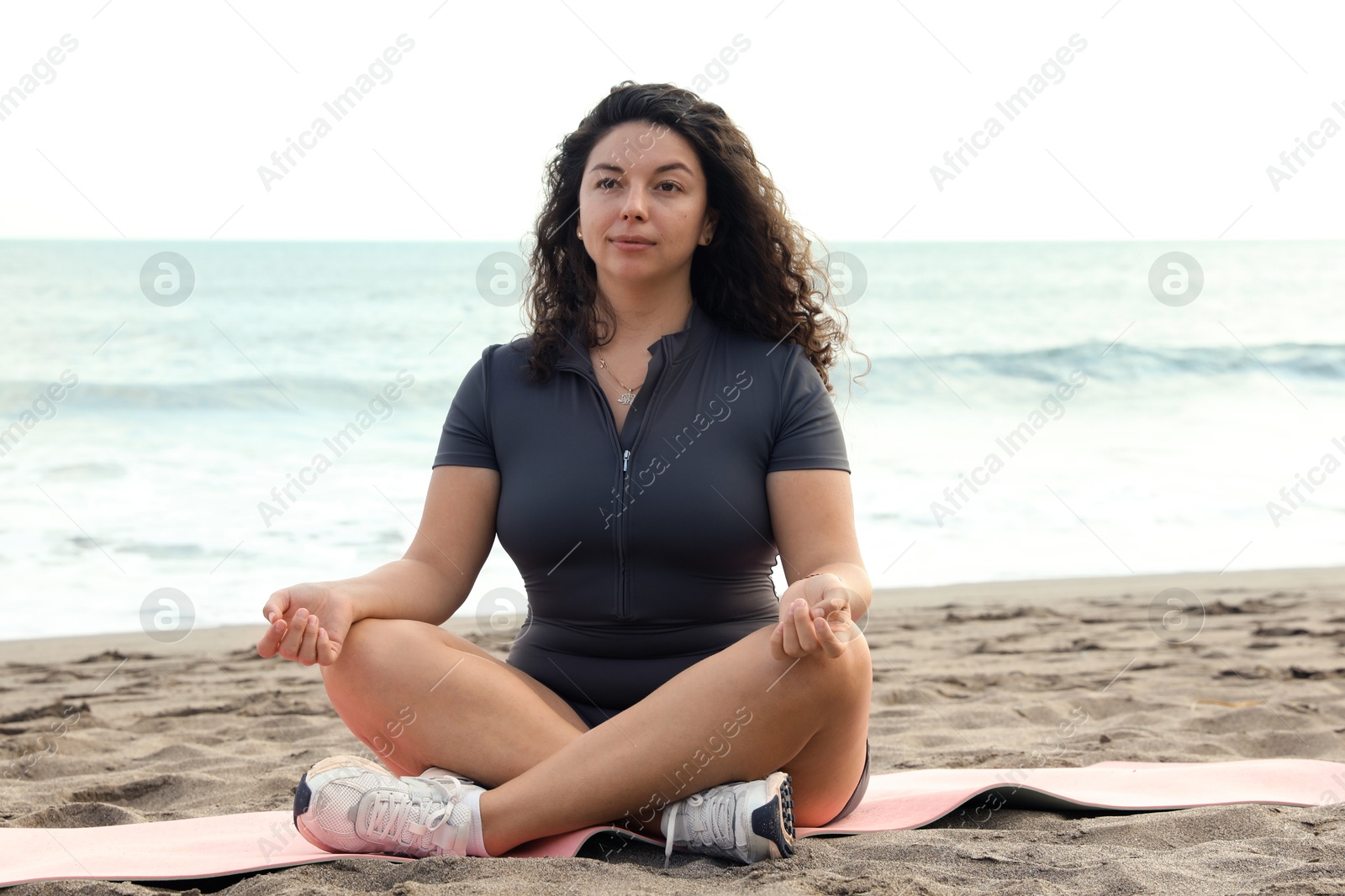 Woman meditating on sandy beach by sea Photo of Woman meditating on sandy beach by sea