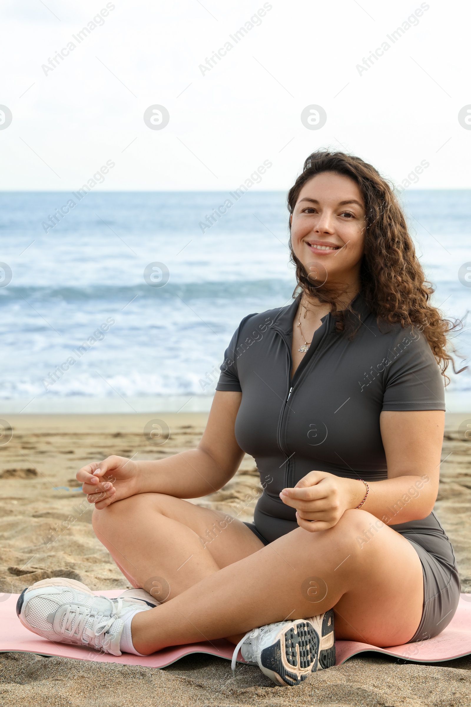 Woman meditating on sandy beach by sea Photo of Woman meditating on sandy beach by sea