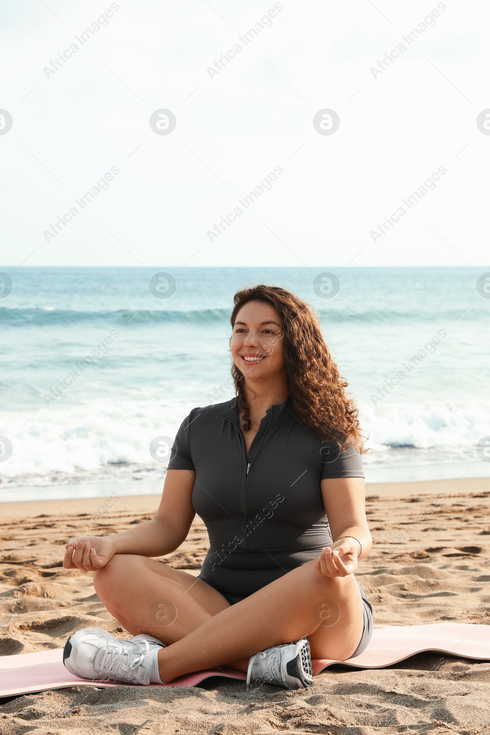 Woman meditating on sandy beach by sea Photo of Woman meditating on sandy beach by sea