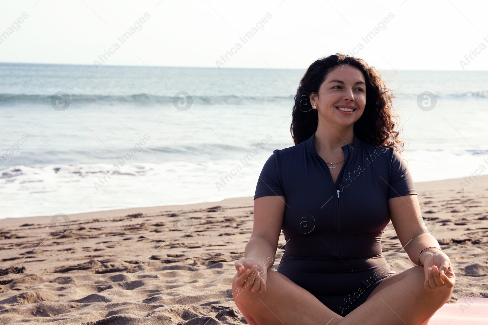 Woman meditating on sandy beach by sea, space for text Photo of Woman meditating on sandy beach by sea, space for text