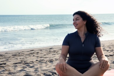 Photo of Beautiful woman relaxing on sandy beach by sea, space for text