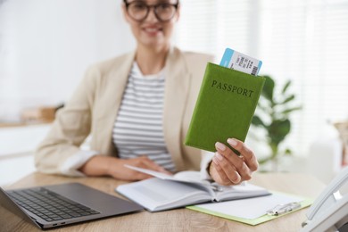 Photo of Travel agent with passport and ticket at wooden table in office, selective focus