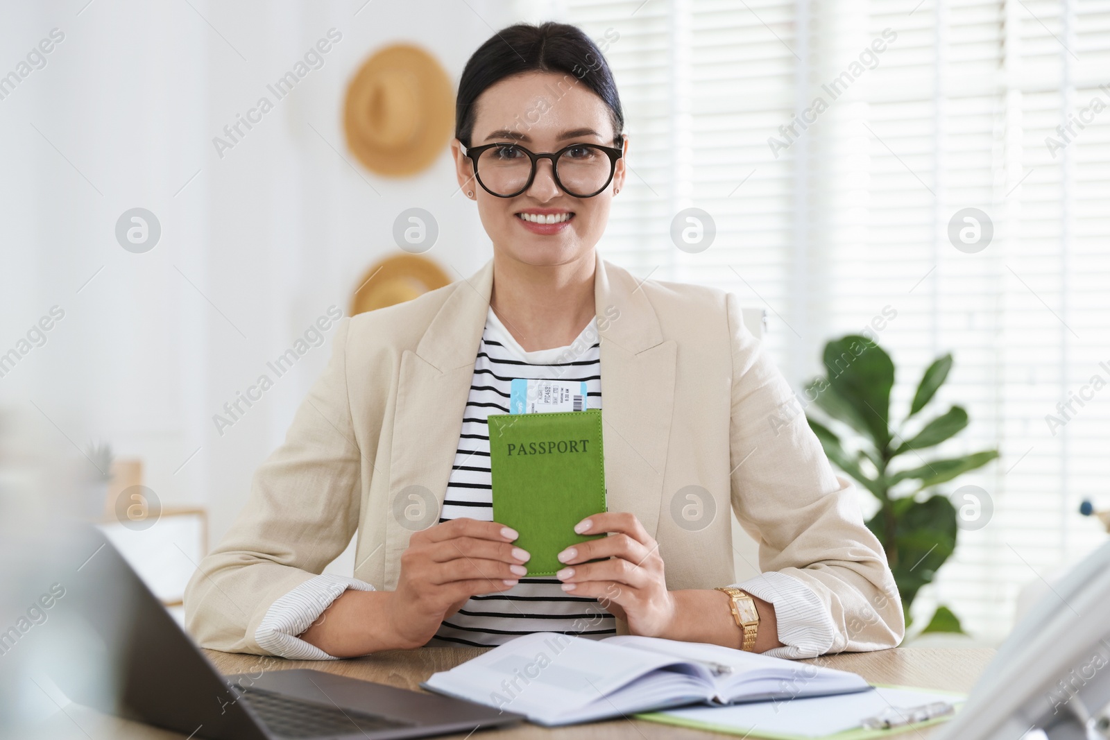 Travel agent with passport and ticket at wooden table in office Photo of Travel agent with passport and ticket at wooden table in office