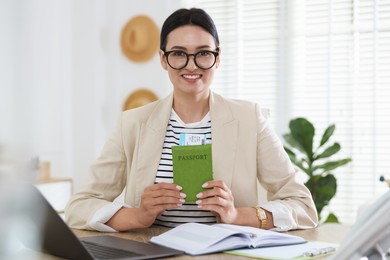 Photo of Travel agent with passport and ticket at wooden table in office