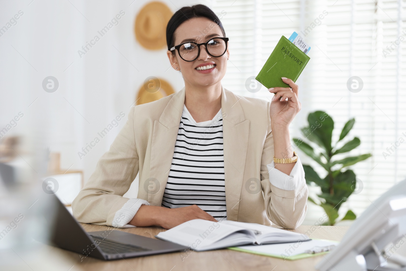 Travel agent with passport and ticket at wooden table in office Photo of Travel agent with passport and ticket at wooden table in office
