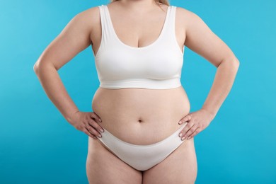 Photo of Weight loss. Plus size woman in underwear on light blue background, closeup