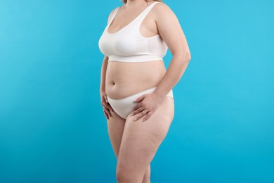 Photo of Weight loss. Plus size woman in underwear on light blue background, closeup