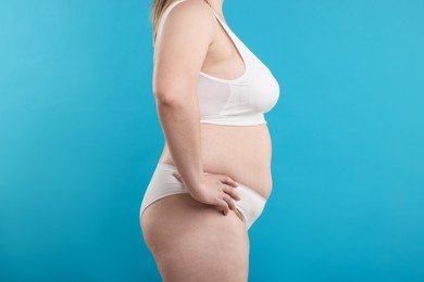 Photo of Weight loss. Plus size woman in underwear on light blue background, closeup