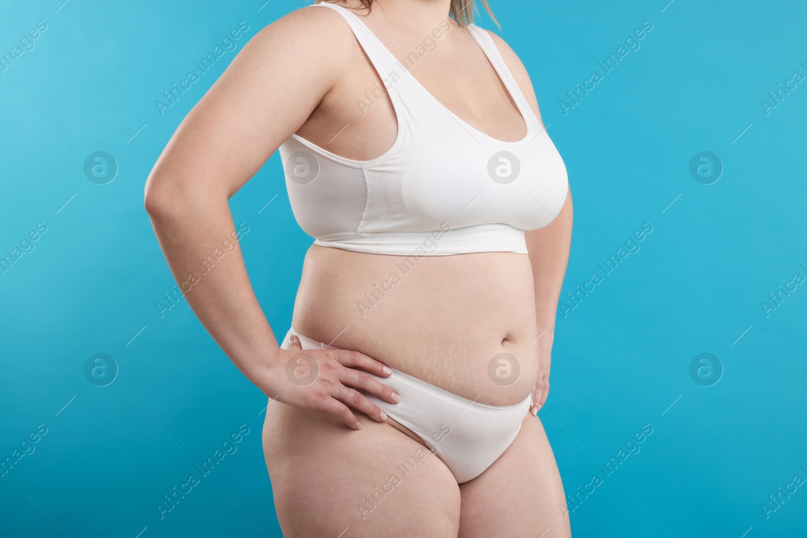 Photo of Weight loss. Plus size woman in underwear on light blue background, closeup