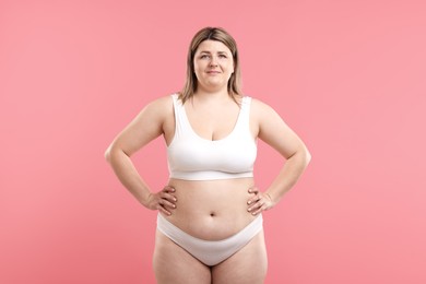 Photo of Weight loss. Plus size woman in underwear on pink background