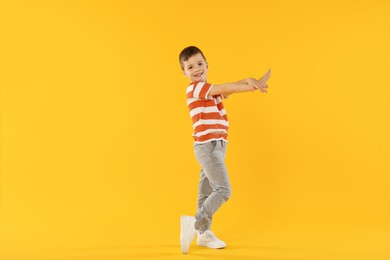 Photo of Happy little boy dancing on orange background