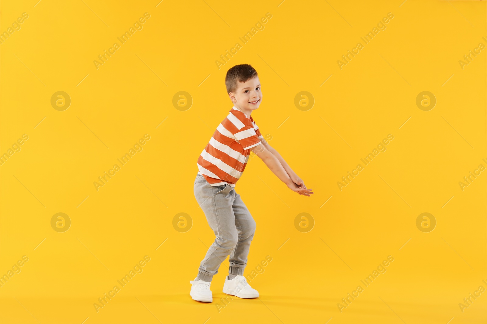 Happy little boy dancing on orange background Photo of Happy little boy dancing on orange background