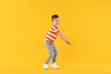 Photo of Happy little boy dancing on orange background