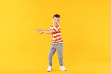 Photo of Happy little boy dancing on orange background
